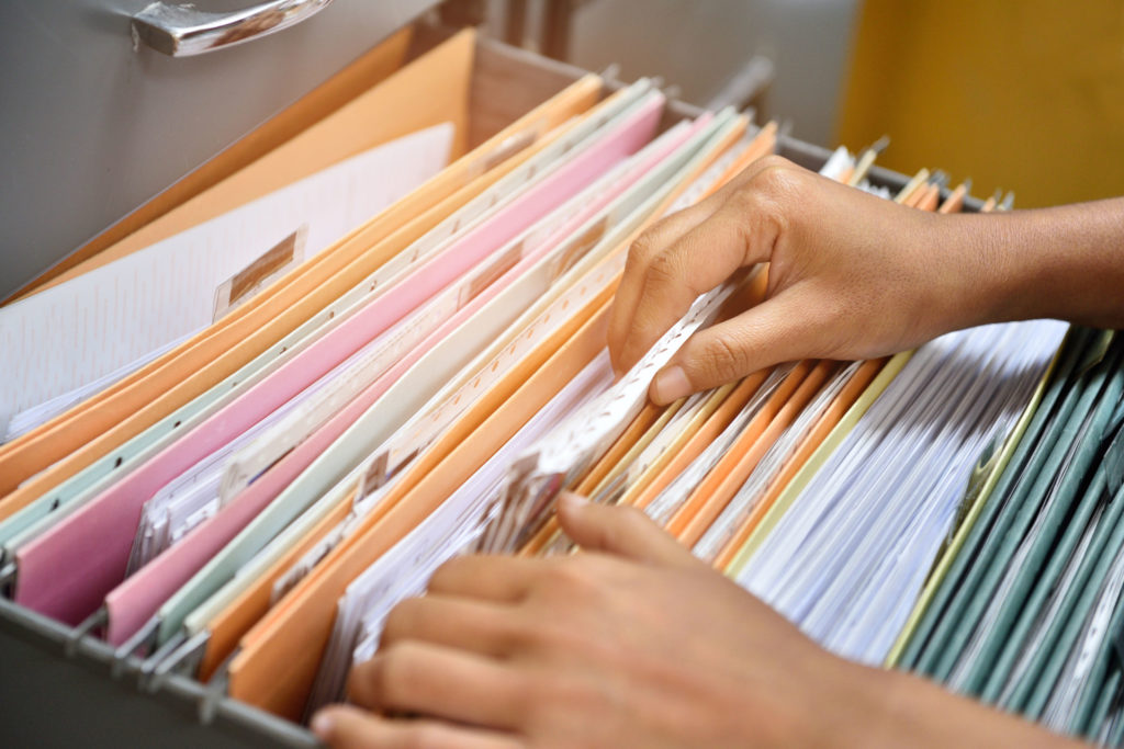 Hands searching through file cabinet and folders